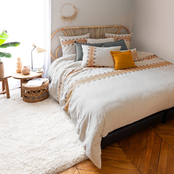 Une chambre avec une parure de lit de couleur beige