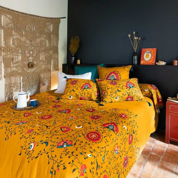 Une chambre avec une parure de lit de couleur jaune