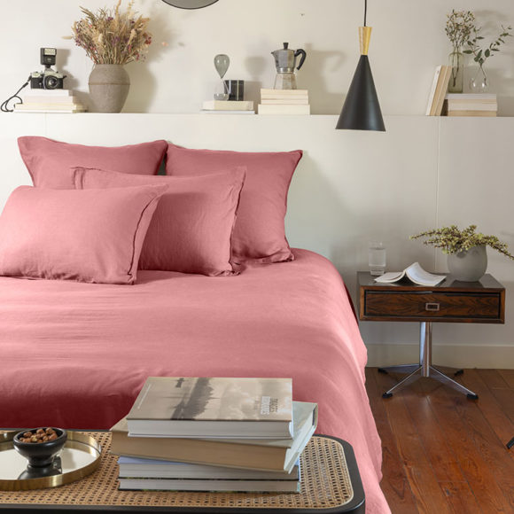 Une chambre avec une parure de lit de couleur rose